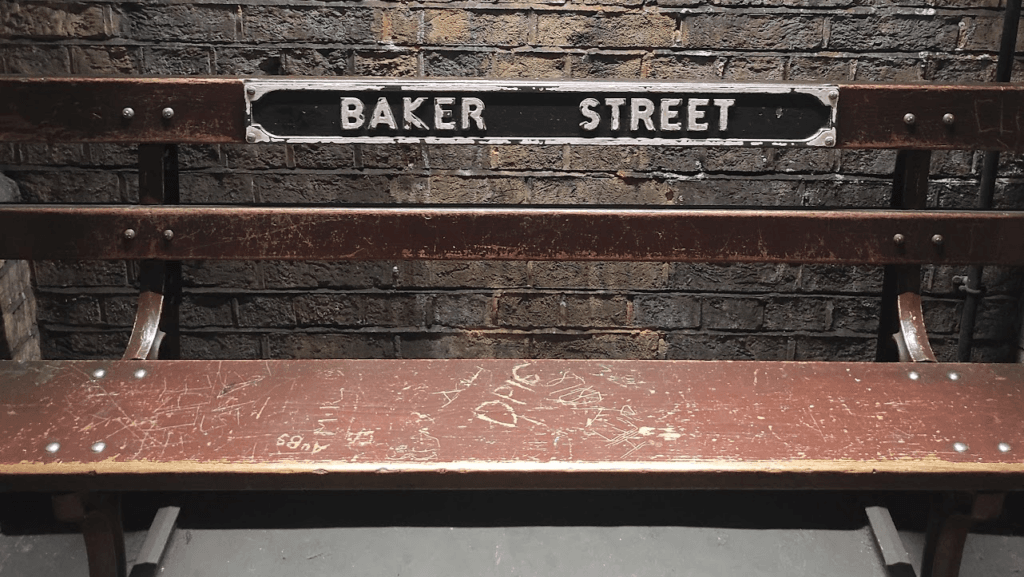 Un'insegna vintage su una panchina della stazione Baker Street. Foto di Carolina Pascutti.